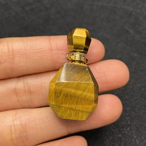 Macro detail of faceted tiger eye stone perfume bottle pendant with gold metal hardware