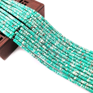 Macro shot of turquoise cylinder stone beads with natural marbling on a wooden box