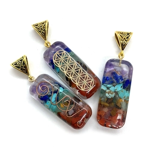 Pendentifs rectangulaires en orgonite avec améthyste et pierres de chakra sur fond blanc