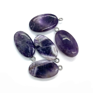 Close-up of five polished oval amethyst stone pendants with silver metal loops