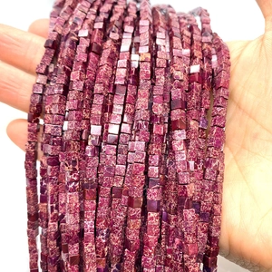 Macro detail of cube-shaped imperial stone beads with purple and red marble texture