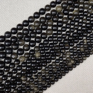 Macro detail of natural obsidian beads showing golden sheen and smooth polished texture