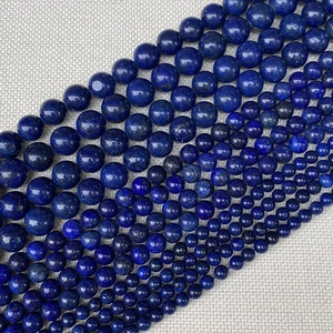 Macro detail of various sizes of natural blue lapis lazuli round beads on linen