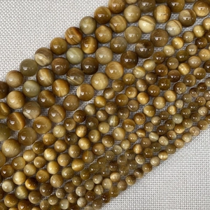 Detailed view of yellow tiger eye stone beads in various sizes with natural cat eye effect