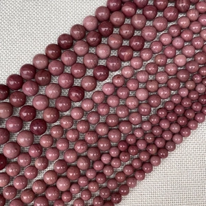 Macro view of natural rose quartz round beads showing silk texture on burlap background