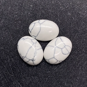 Drie ovale witte howliet cabochons met natuurlijke grijze aders op grijze textuur
