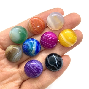 Hand holding nine pieces of polished multi-color striped agate round cabochon stones