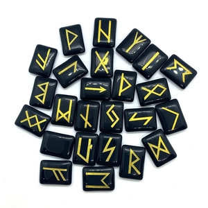 Macro detail of black rune stones with engraved gold Elder Futhark symbols for divination