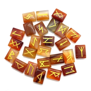 Polished red agate rune stones with golden engraved Norse alphabets on white background