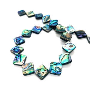 Macro detail of square abalone shell beads showing vibrant iridescent textures for DIY jewelry
