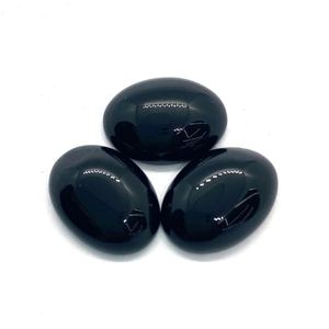 Drie gepolijste ovale zwarte onyx cabochon stenen voor DIY sieraden op witte achtergrond