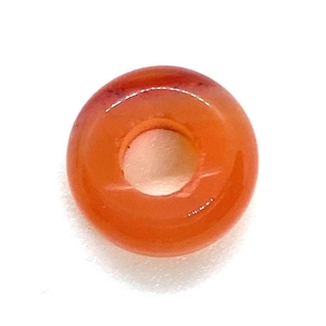 Close-up of translucent orange-red natural stone donut bead with a smooth polished finish