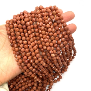 Perle sfaccettate di 6mm in pietra del sole per gioielli tenute in mano su sfondo bianco