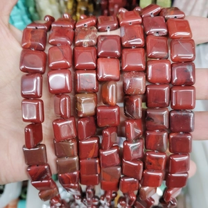 Macro shot of square red jasper loose beads for DIY jewelry making on palm