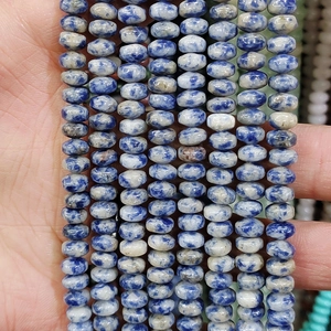 Detail of hand holding blue and white sodalite gemstone wheel beads for jewelry making