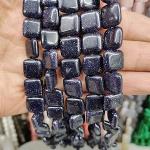 Macro shot of dark blue goldstone square beads with shimmering metallic starry effects