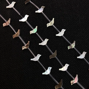 Macro shot of bird-shaped natural shell beads with iridescent luster for DIY jewelry