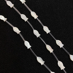 Detailed macro view of fish-shaped natural shell beads with iridescent pearl luster for DIY