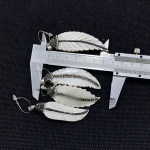 Makroaufnahme von Muschel-Federanhänger mit Strasssteinen und 5,8 cm Messschieber