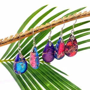 Macro detail of drop-shaped natural stone earrings hanging on a natural branch leaf