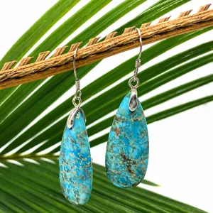 Detailed close-up of blue turquoise teardrop earrings hanging on a natural wood branch