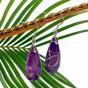 Detailed view of purple teardrop stone earrings hanging on a natural wooden branch
