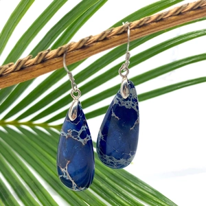 Deep blue teardrop turquoise earrings on green palm leaf with silver hooks