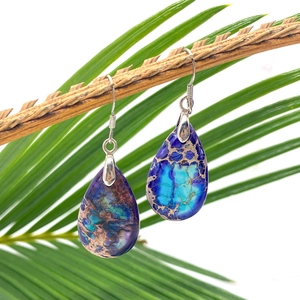 Handmade teardrop natural stone earrings with purple turquoise patterns on wooden branch