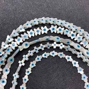 Perline di conchiglia naturale con malocchio blu in forme di stella, pesce e croce