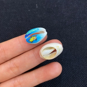 Close-up of hand-painted turtle sea shells on fingertips showing natural texture and size