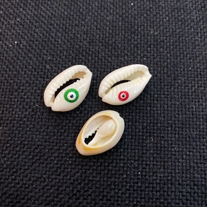 Macro detail of natural cowrie shell beads with hand-painted evil eye patterns for DIY jewelry
