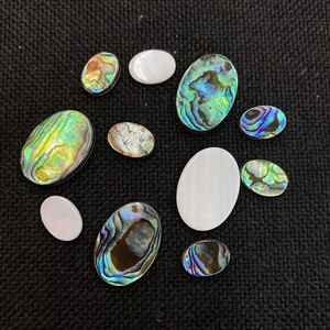 Macro shot of oval natural abalone and mother of pearl flatback cabochons for DIY jewelry
