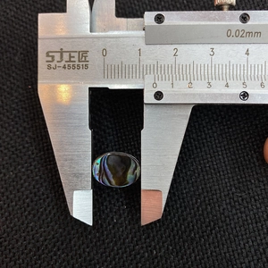 Macro shot showing 15mm oval abalone shell bead dimension measured by caliper