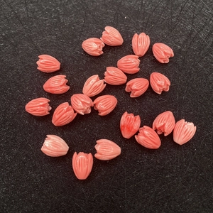 Detailed macro view of coral pink tulip-shaped beads with carved petal textures