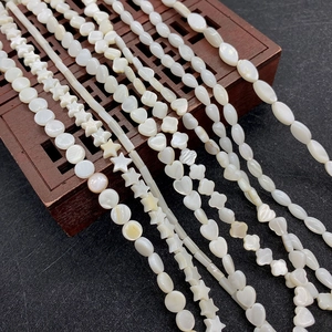 Macro shot of white shell beads in star, heart and flower shapes for DIY jewelry