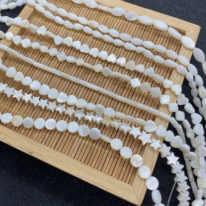 Macro detail of white natural mother of pearl beads in star and heart shapes on bamboo tray