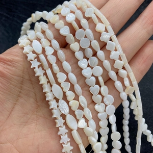 Macro shot of natural white mother of pearl shell beads in various star and heart shapes