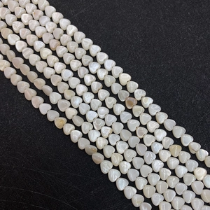 Macro detail of heart-shaped natural shell beads with pearl luster for DIY jewelry
