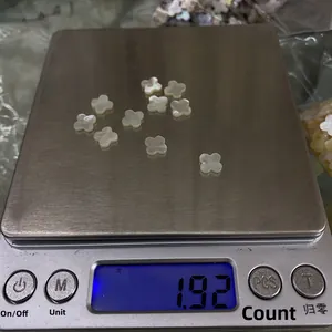 Macro-opname van tien 8mm witte schelp klaverblaadjes gewogen op een weegschaal