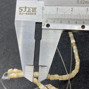 Measuring 4mm natural white square shell beads with a digital caliper for jewelry making