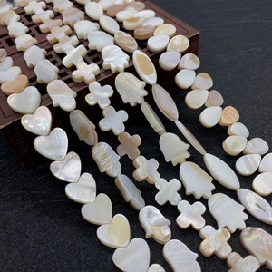 Macro shot of natural mother of pearl shell beads in heart, cross and teardrop shapes