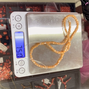 Macro shot of 15g orange cubic natural shell beads on digital scale for DIY jewelry
