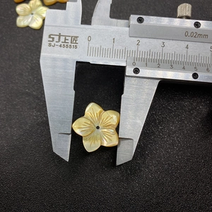 Primer plano de una cuenta de nácar de 15mm en forma de flor medida con un pie de rey