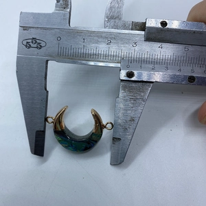 Macro view of a 26mm crescent moon shell pendant with golden connector on a caliper scale