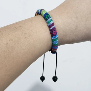 Detail of bohemian hand-woven colorful cotton bracelet with adjustable black cords and beads