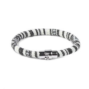 Detail van de zwart-witte geweven textuur en de zilveren magnetische sluiting van de armband