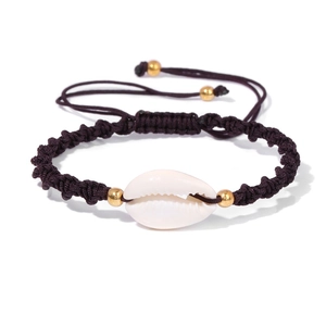 Detail eines handgewebten Muschelarmbands mit echter Kaurimuschel und Goldperlen