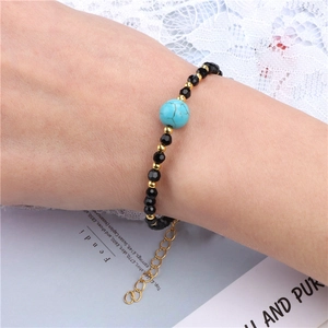 Verstelbare armband van zwarte kralen met turquoise steen en goudkleurige sluiting
