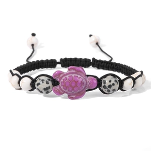 Detailed macro view of turtle charm and speckled stone beads on a woven bracelet
