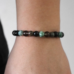 Detalle de pulsera hecha a mano con cuentas de cuarzo ahumado y turquesa en la muñeca